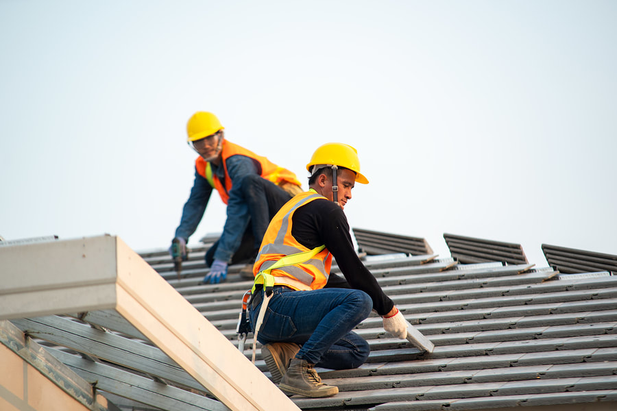 roofers working on a commercial roof with hard hats on