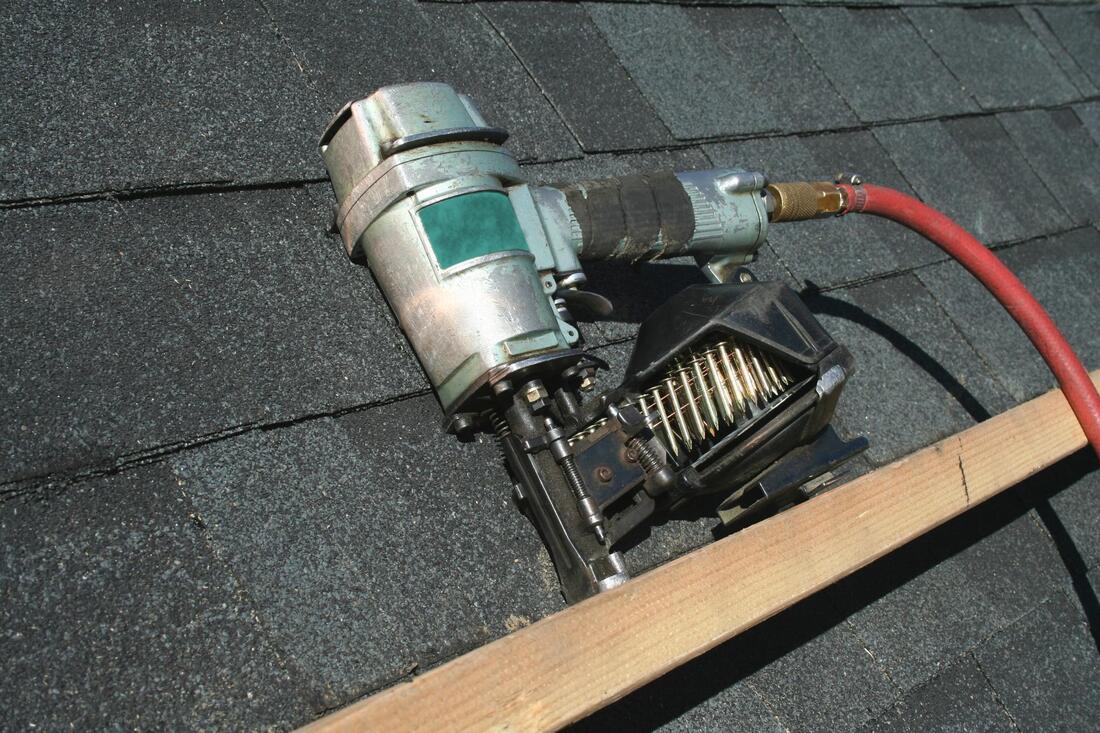 a roofing air nailer sitting on a wood cleat waiting to be used on a roof installation